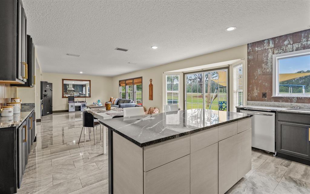 A kitchen with a dark stone island, gray cabinets, and tile floors overlooking a backyard — 5312 CYPRESS LINKS, ELKTON, FL