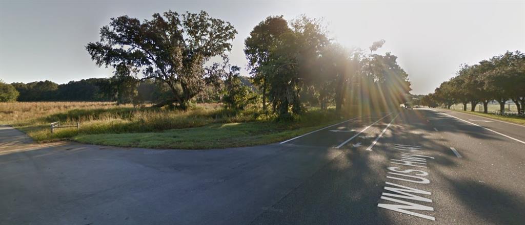 A view of a grassy field and large trees next to a paved highway intersection — TBD HIGHWAY 441, ALACHUA, FL