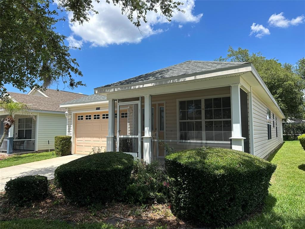 A single-story house with light siding, a screened front porch, and a tan garage door — 25335 CRANES ROOST CIRCLE, LEESBURG, FL