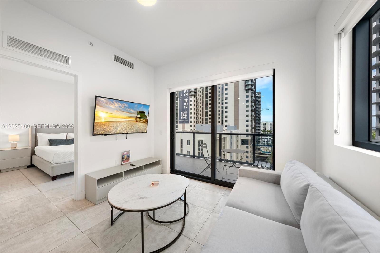 A modern living room with a sofa, coffee table, television, and an adjacent bedroom — 239 SW 9th St # 1202, Miami FL 33130, MIAMI, FL