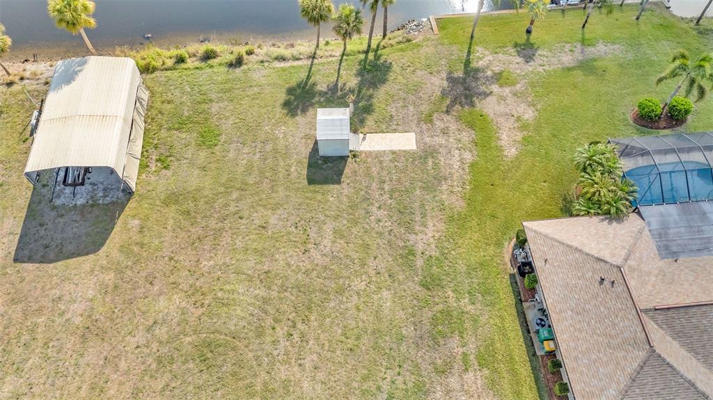 An aerial view shows a large grassy backyard with a metal carport and a shed — 2410 /2418 COMO STREET, PORT CHARLOTTE, FL