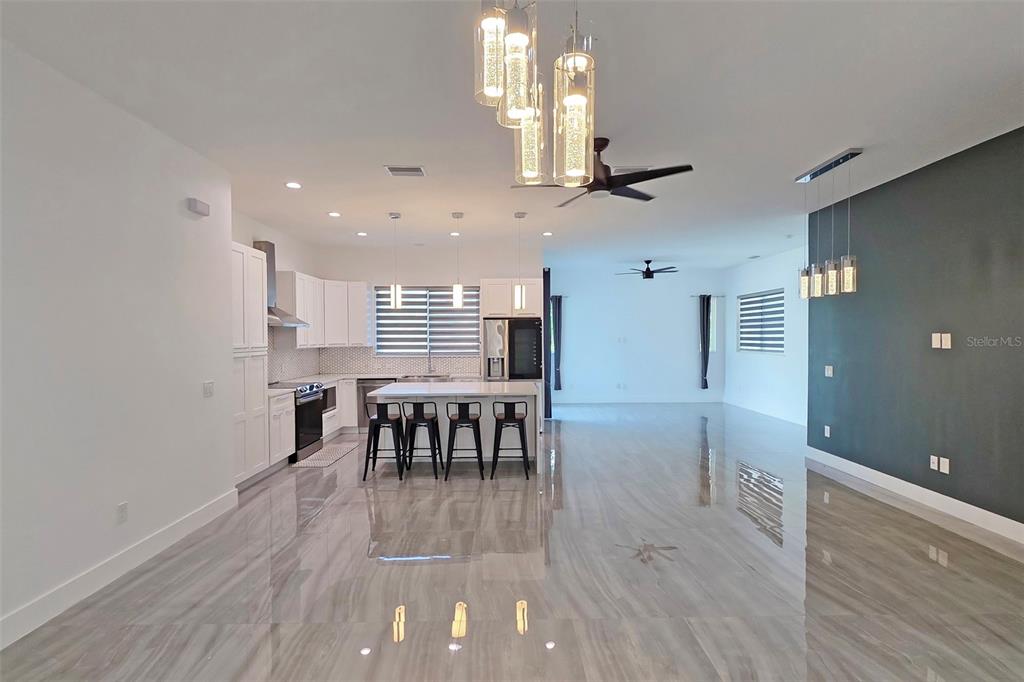 A modern open-concept kitchen features white cabinetry, a central island with stools, and tiled floors — 3017 PINE STREET, BRADENTON, FL