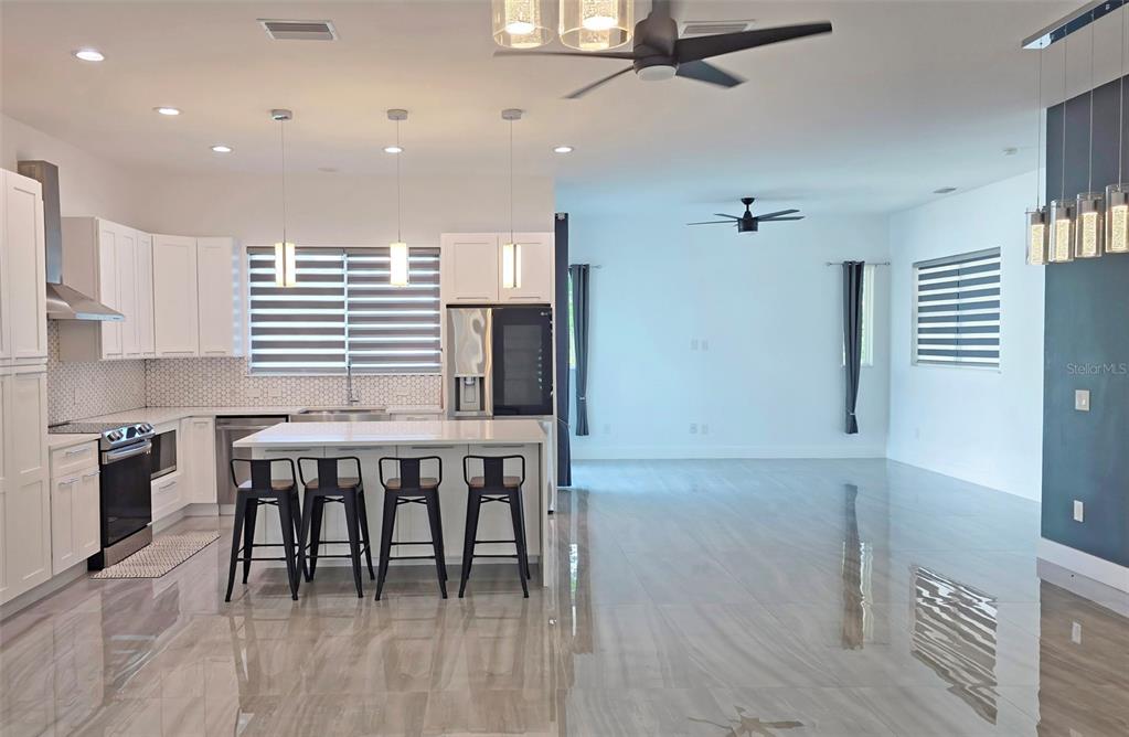 A modern kitchen with white cabinetry, a central island, and bar stools in an open-concept space — 3017 PINE STREET, BRADENTON, FL