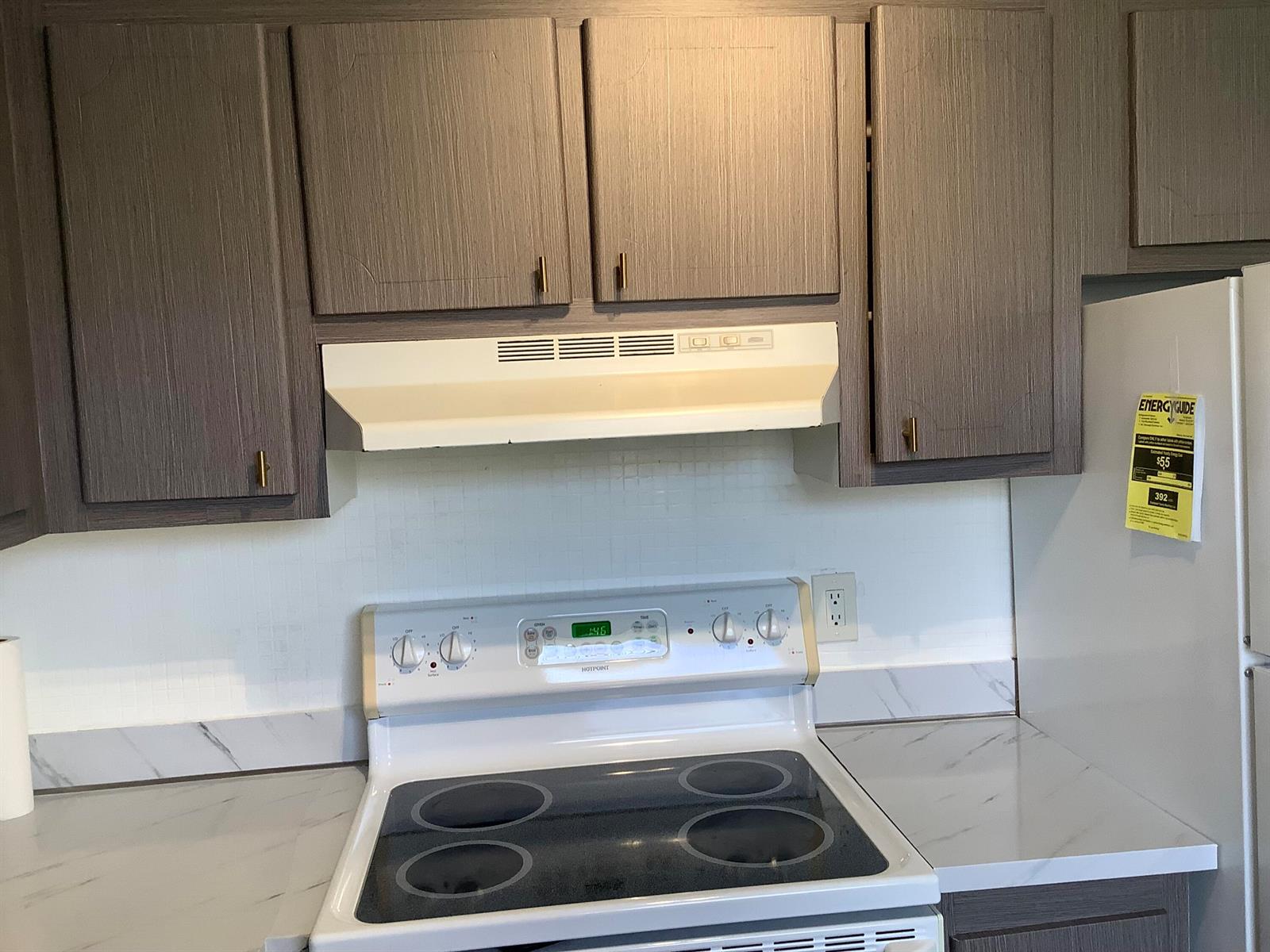 A kitchen features gray wood-grain cabinets, a white electric stove, and white marble-look countertops — 189 Saxony # 189, Delray Beach FL 33446, DELRAY BEACH, FL