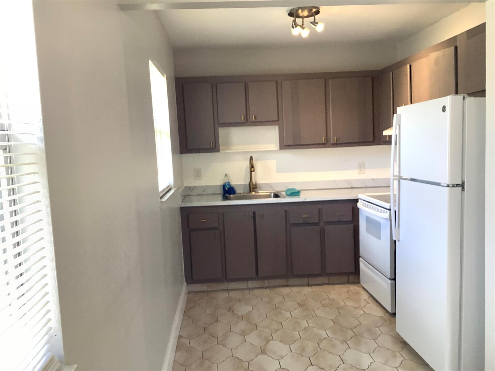 A kitchen features brown cabinets, white countertops, a white refrigerator, and patterned tile flooring — 189 Saxony # 189, Delray Beach FL 33446, DELRAY BEACH, FL