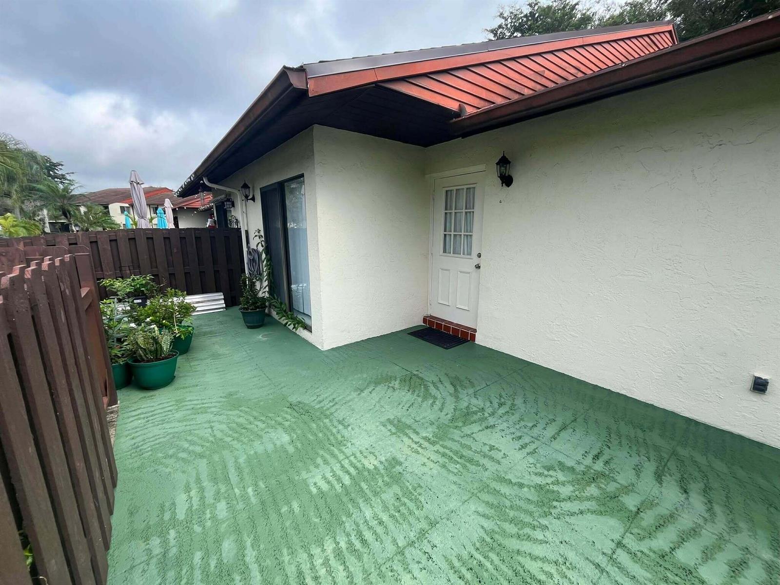 A patio with green painted concrete flooring, a white door, and a wooden privacy fence — 4863 Sable Pine Circle # D, West Palm Beach FL 33417, WEST PALM BEACH, FL