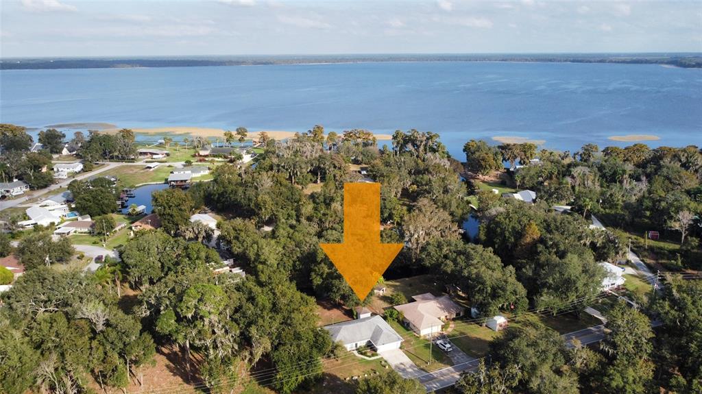 An aerial view shows a house with a gray roof surrounded by trees near water — 4542 TIMBERLANE ROAD, LAKE WALES, FL