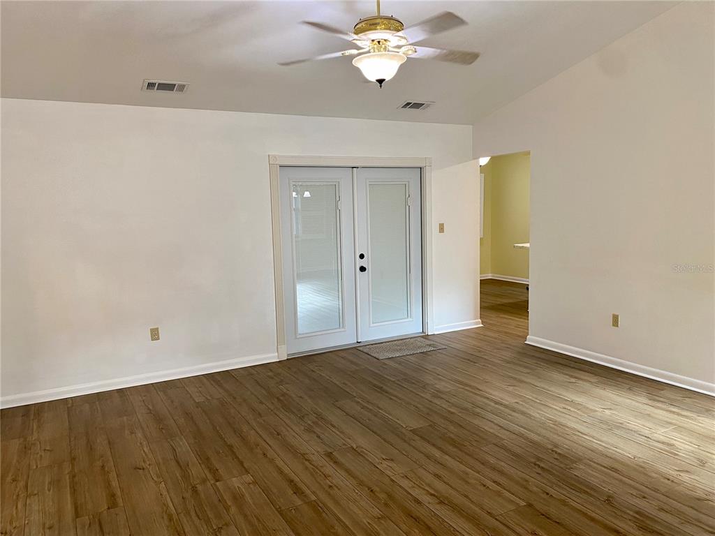 A living room with wood-look flooring, a ceiling fan, and double glass doors — 4542 TIMBERLANE ROAD, LAKE WALES, FL