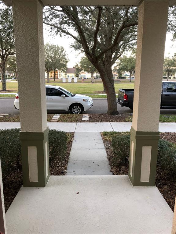 A view from a covered front porch looking out toward a sidewalk, street, and trees — 12982 KEGAN STREET, WINDERMERE, FL