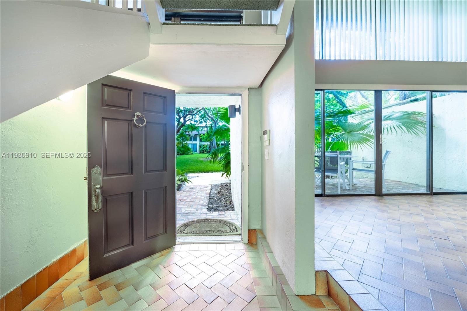 An open front door reveals a tiled entryway with a staircase and a patio view — 19212 NE 25th Ave # 283D, Miami FL 33180, MIAMI, FL