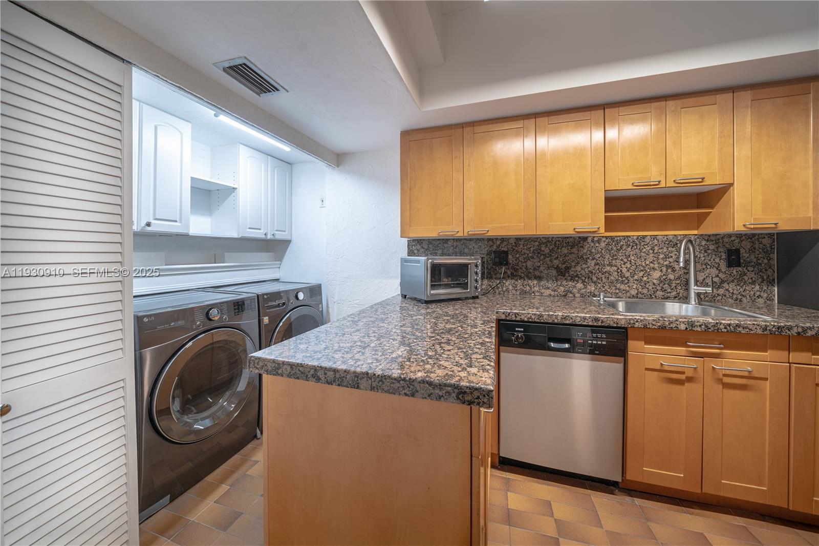 A kitchen area features light wood cabinets, granite countertops, a dishwasher, and laundry appliances — 19212 NE 25th Ave # 283D, Miami FL 33180, MIAMI, FL