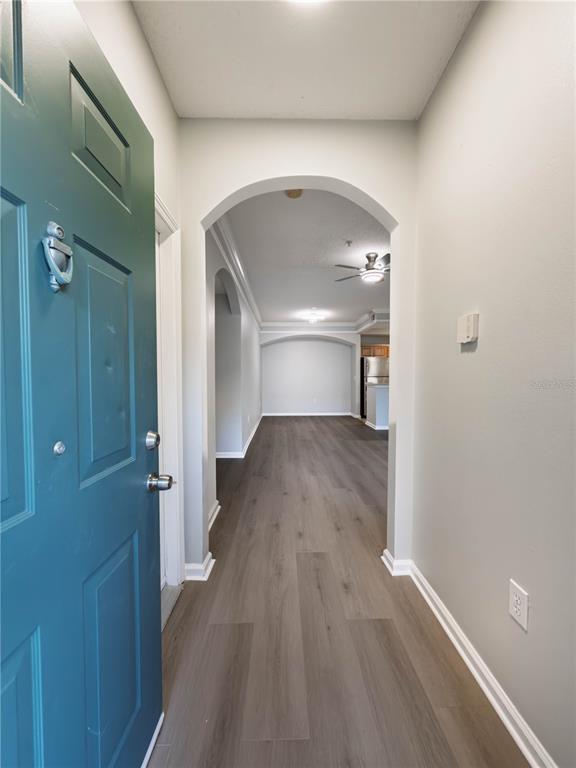 An entryway with a teal door leads into a hallway with wood-look flooring and arches — 12203 WILD IRIS WAY UNIT 108, ORLANDO, FL