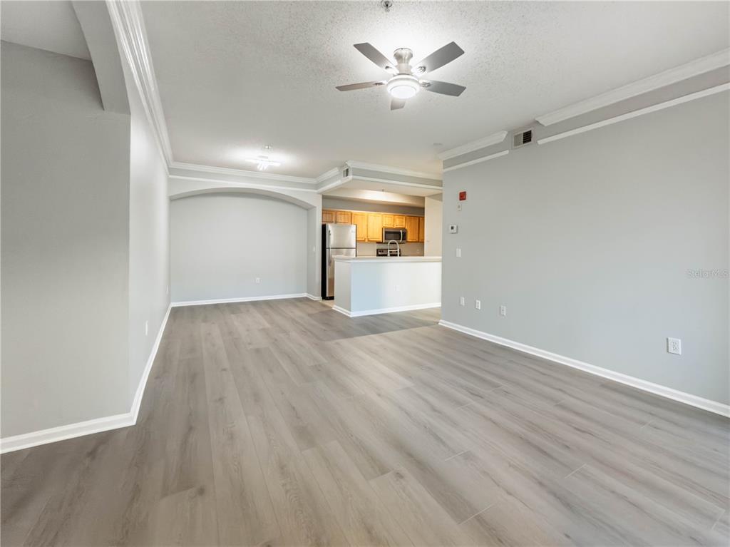 An open-concept living area features light gray walls, wood-look flooring, and a kitchen with cabinets — 12203 WILD IRIS WAY UNIT 108, ORLANDO, FL
