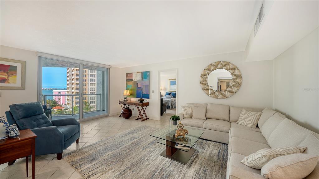 A living room with tile floors, a blue armchair, and a balcony overlooking the water — 1111 N GULFSTREAM AVENUE UNIT 10E, SARASOTA, FL