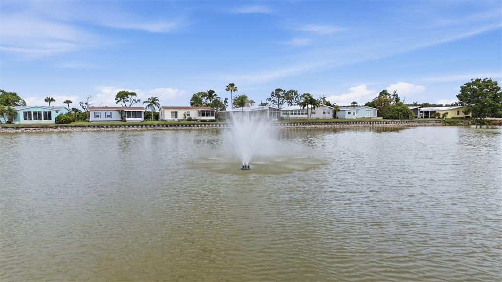 A water fountain sits in the center of a lake in front of several houses — 520 IMPERIAL DRIVE, NORTH PORT, FL