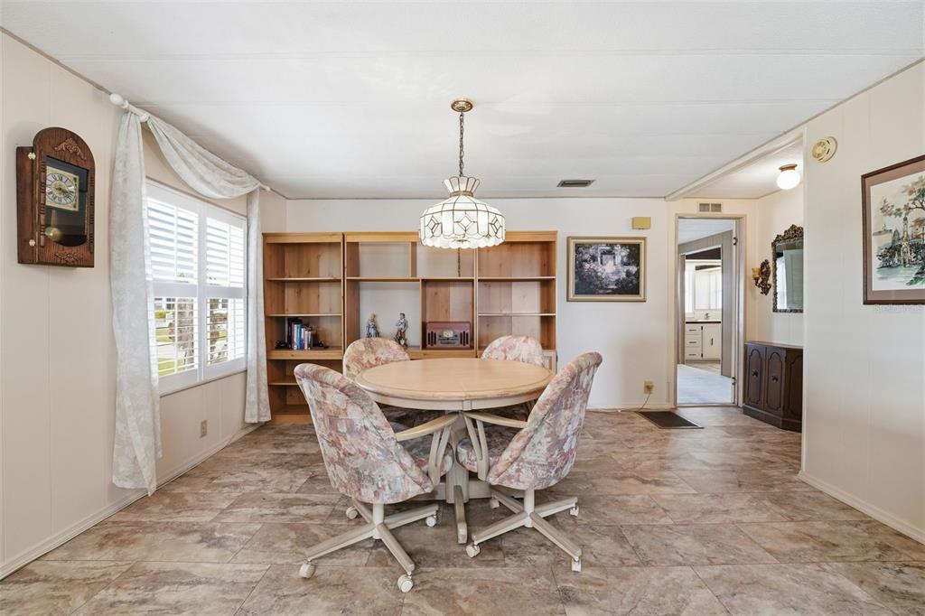 A dining room features a round table with four floral chairs, shelving, and tile flooring — 520 IMPERIAL DRIVE, NORTH PORT, FL