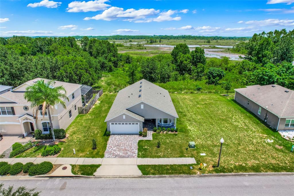 An aerial view shows a gray single-story house with a paved driveway and large yard — 3050 SUNSCAPE TERRACE, GROVELAND, FL