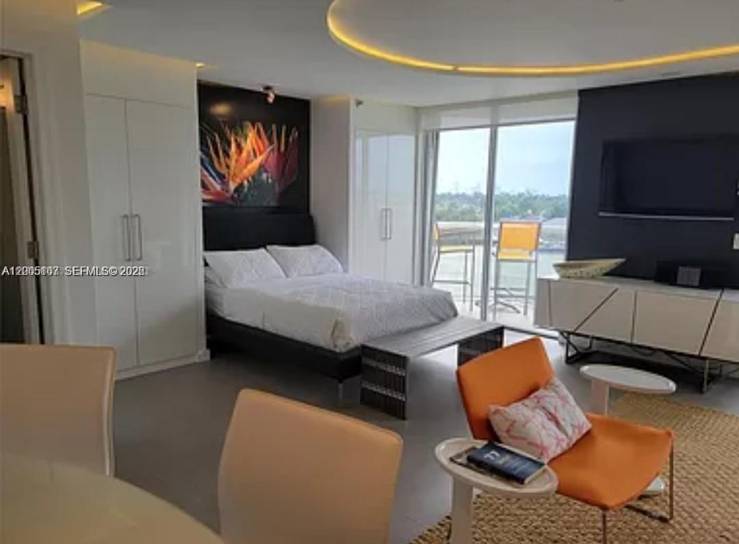 This modern bedroom features a bed, a seating area, and a balcony with water views — 5880 Collins Ave # 604, Miami Beach FL 33140, MIAMI BEACH, FL
