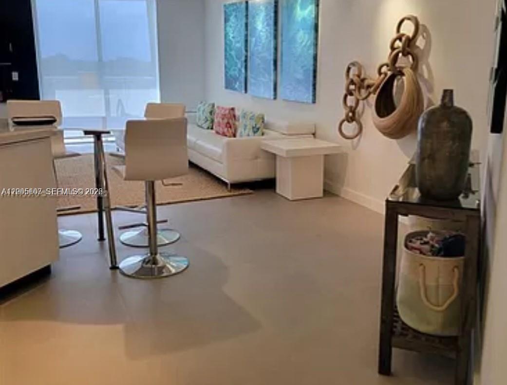 A modern living and dining area features white furniture, a neutral rug, and wall art — 5880 Collins Ave # 604, Miami Beach FL 33140, MIAMI BEACH, FL