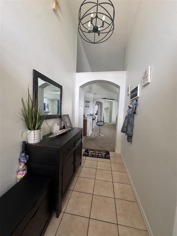 A tiled entryway features a dark wooden console table, a mirror, and a vaulted ceiling — 4612 FALCON AVENUE, KISSIMMEE, FL