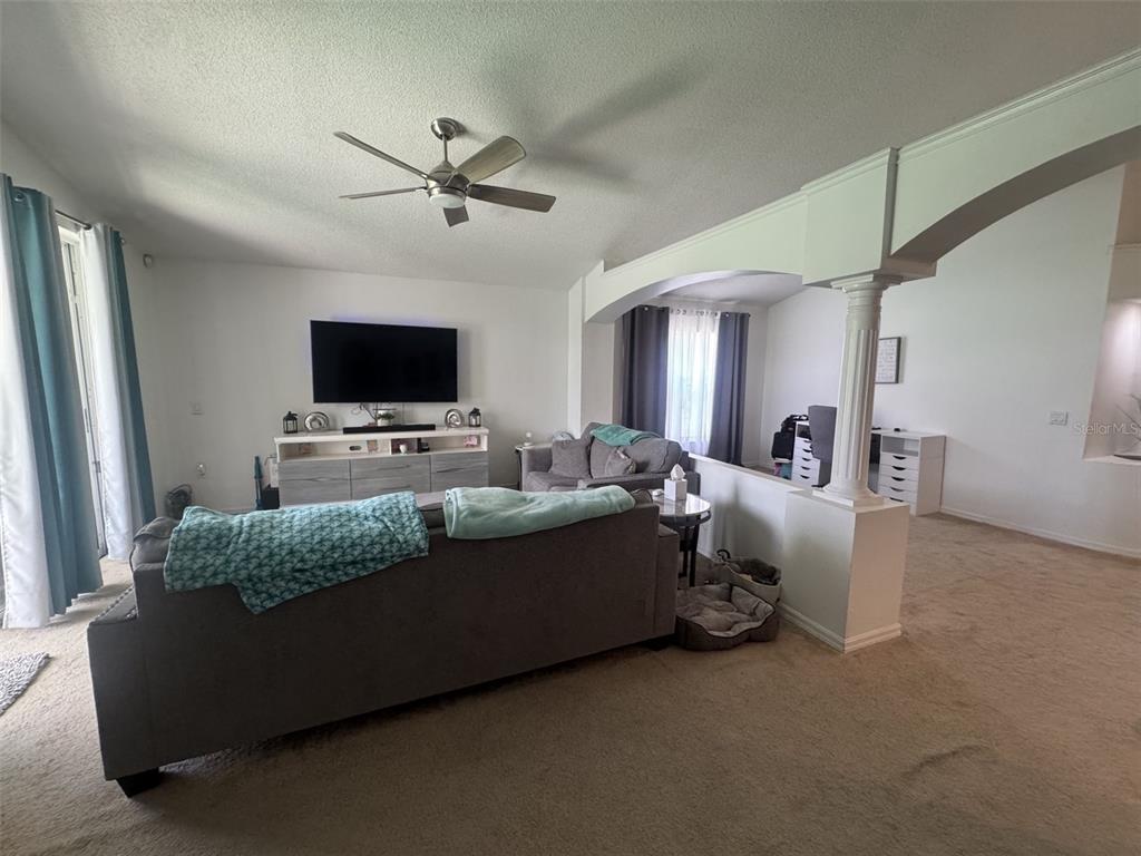 A living room features a gray sofa, a television on a console, and a ceiling fan — 4612 FALCON AVENUE, KISSIMMEE, FL
