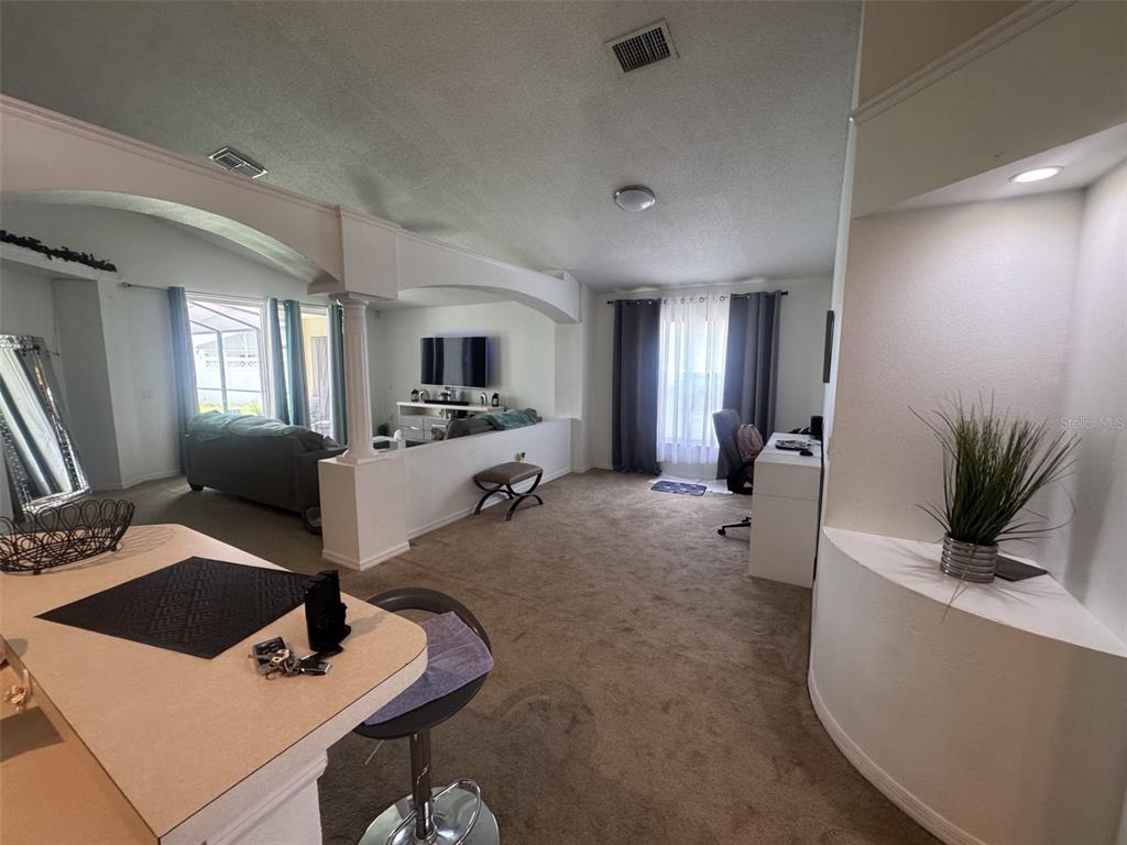 A living room with carpeted floors, a partial wall, and a view of a patio — 4612 FALCON AVENUE, KISSIMMEE, FL