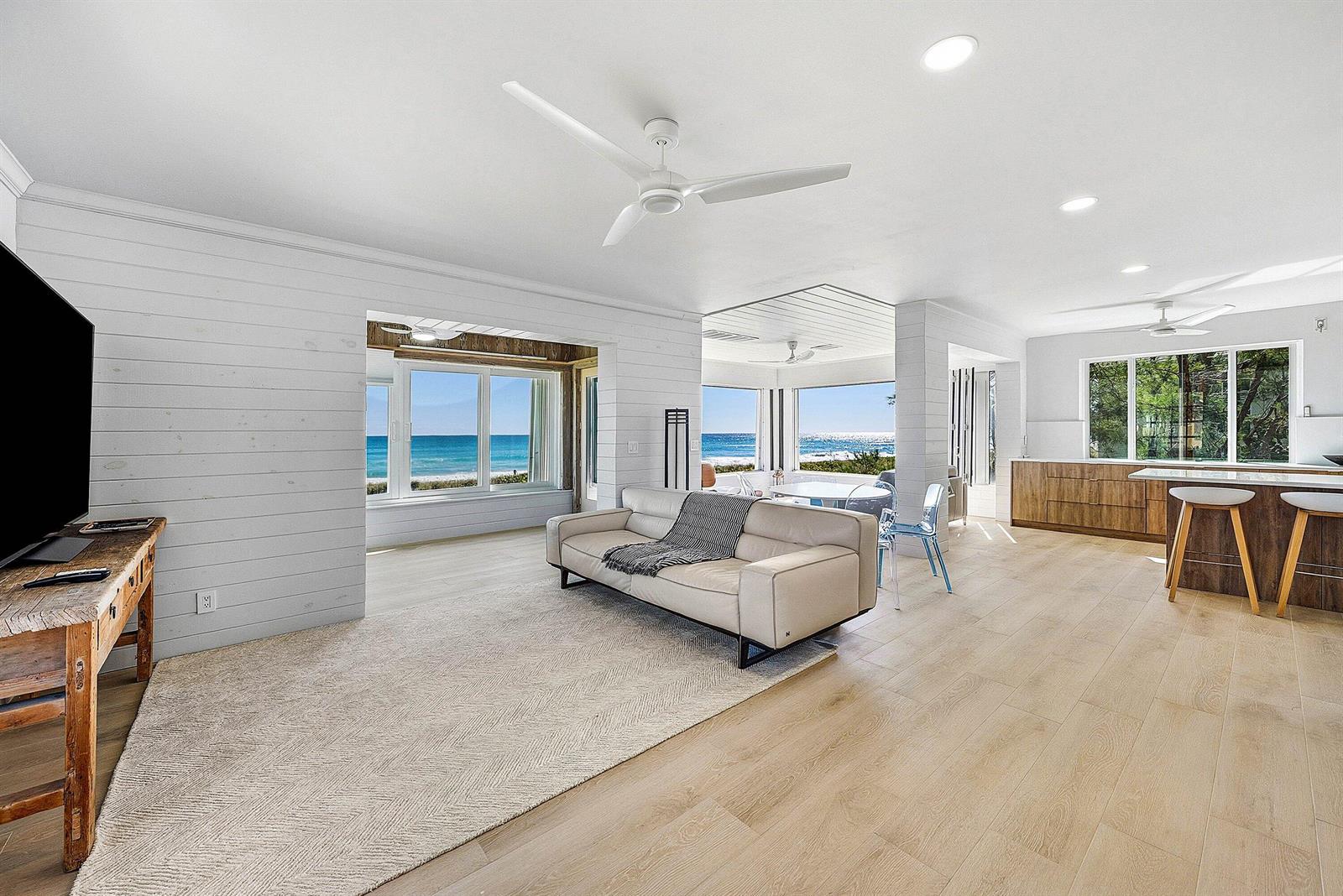 An open-concept living area features light wood floors, white shiplap walls, and ocean views — 2075 S Ocean Boulevard # 4b, Delray Beach FL 33483, DELRAY BEACH, FL