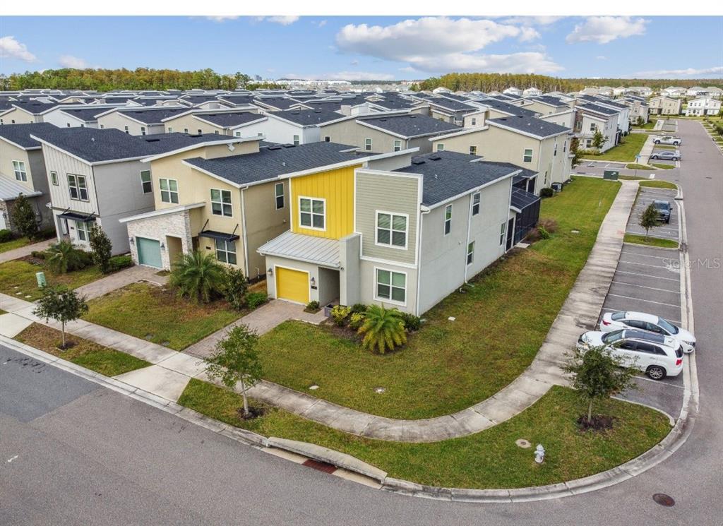 An aerial view shows a modern two-story townhouse with a yellow accent wall and garage — 2784 BOOKMARK DRIVE, KISSIMMEE, FL