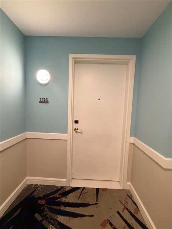 A white door with a gold handle and number 1116 sits between light blue walls — 3151 SUNSET WALK DRIVE UNIT 116, KISSIMMEE, FL