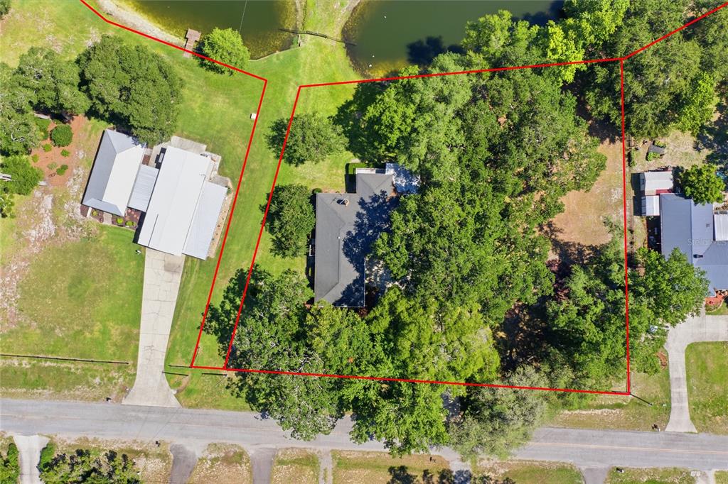 An aerial view shows a house on a wooded lot with a red property boundary — 561 SE 28TH STREET, MELROSE, FL