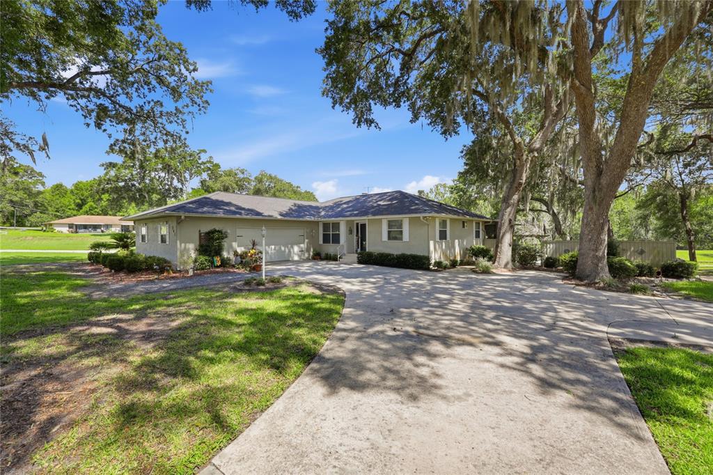 A single-story house with a concrete driveway and large oak trees in the front yard — 561 SE 28TH STREET, MELROSE, FL