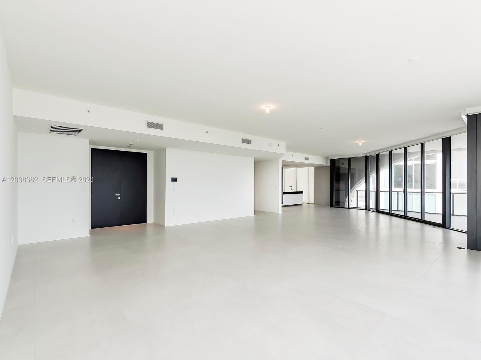 A spacious, minimalist room features white walls, light tile flooring, and floor-to-ceiling windows — 1000 Biscayne Blvd # 2002, Miami FL 33132, MIAMI, FL