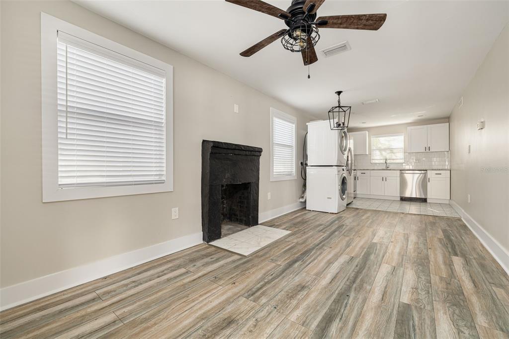 A room with wood-look flooring, a black fireplace, a ceiling fan, and an adjacent kitchen — 106 W HAYA STREET, TAMPA, FL