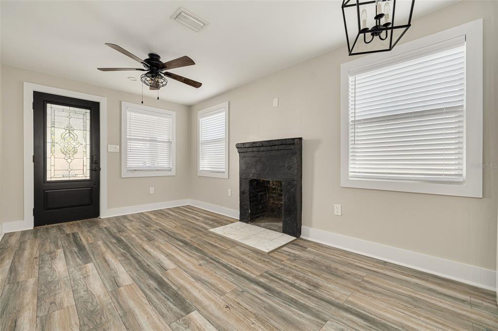 A living room features light wood-look flooring, a black fireplace, and a black front door — 106 W HAYA STREET, TAMPA, FL