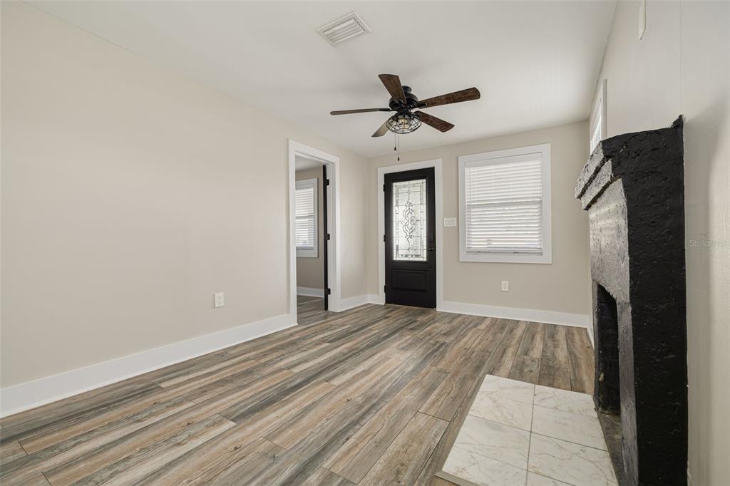 A living room features wood-look flooring, a black fireplace, a ceiling fan, and a glass-paneled door — 106 W HAYA STREET, TAMPA, FL