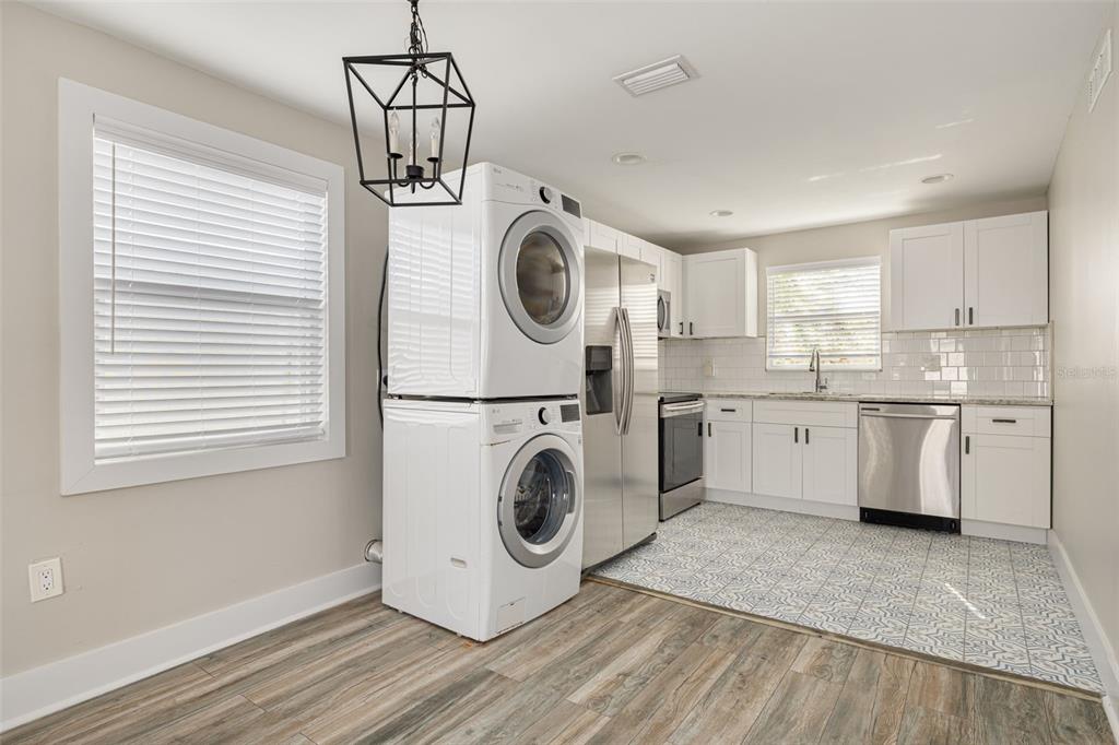 A kitchen with white cabinets, stainless steel appliances, a stacked washer-dryer, and patterned tile flooring — 106 W HAYA STREET, TAMPA, FL