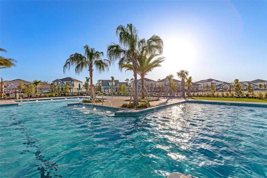 A swimming pool with a central island featuring palm trees and water jets — 3145 BROOKHOLLOW WAY, MINNEOLA, FL