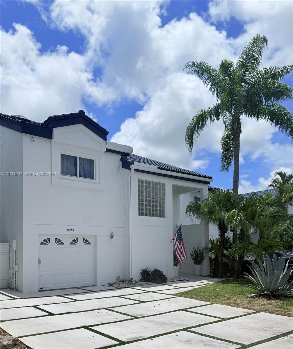A two-story white house features a single-car garage, a palm tree, and a paved driveway — 21251 NE 3rd Ct, Miami FL 33179, MIAMI, FL