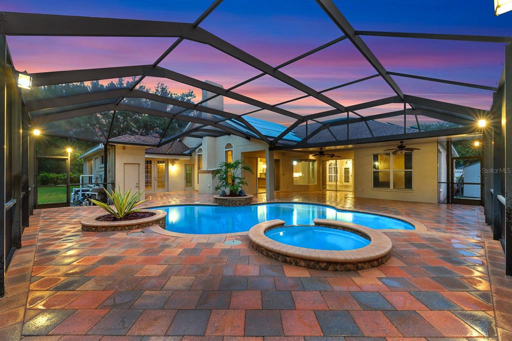 A screened-in patio features a swimming pool, a raised spa, and multi-colored paver flooring — 5711 TANAGERSIDE ROAD, LITHIA, FL