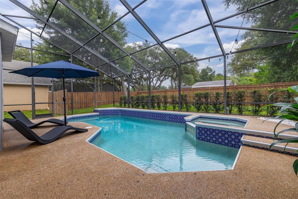 A screened-in swimming pool and spa with a patio and lounge chairs in a backyard — 663 CHARRICE PLACE, SANFORD, FL