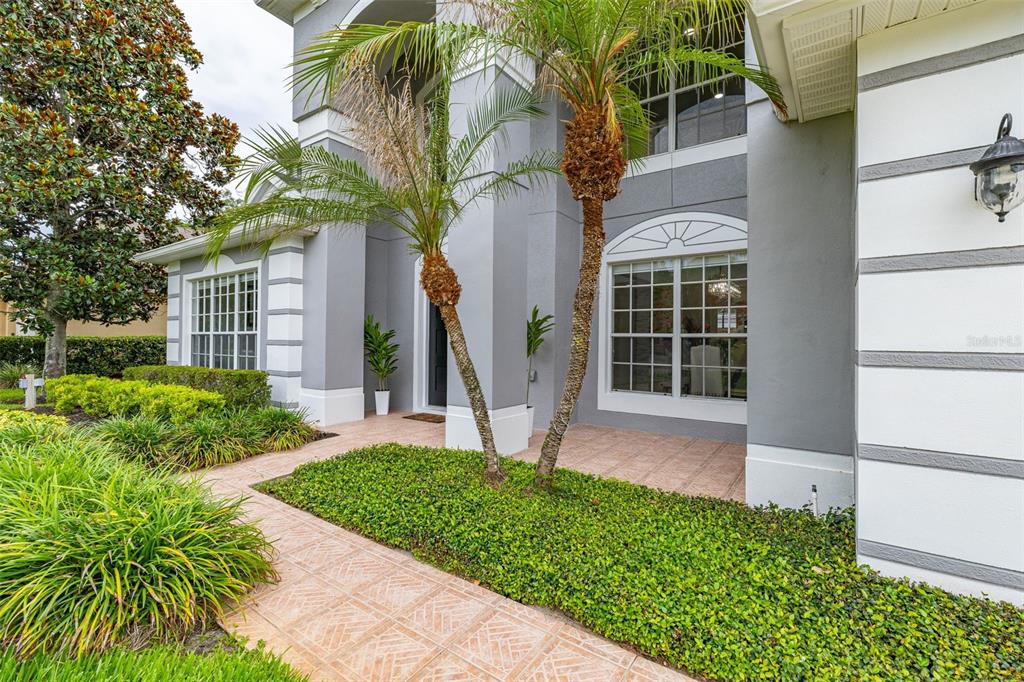 The exterior of a two-story gray house features a tiled entryway and two palm trees — 663 CHARRICE PLACE, SANFORD, FL