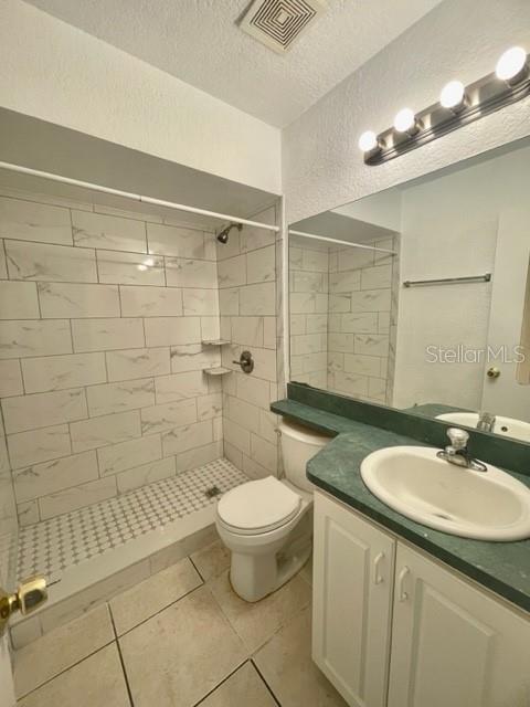 A bathroom features a tiled shower, a white toilet, and a vanity with a green countertop — 730 WYMAN COURT UNIT 730, ORLANDO, FL