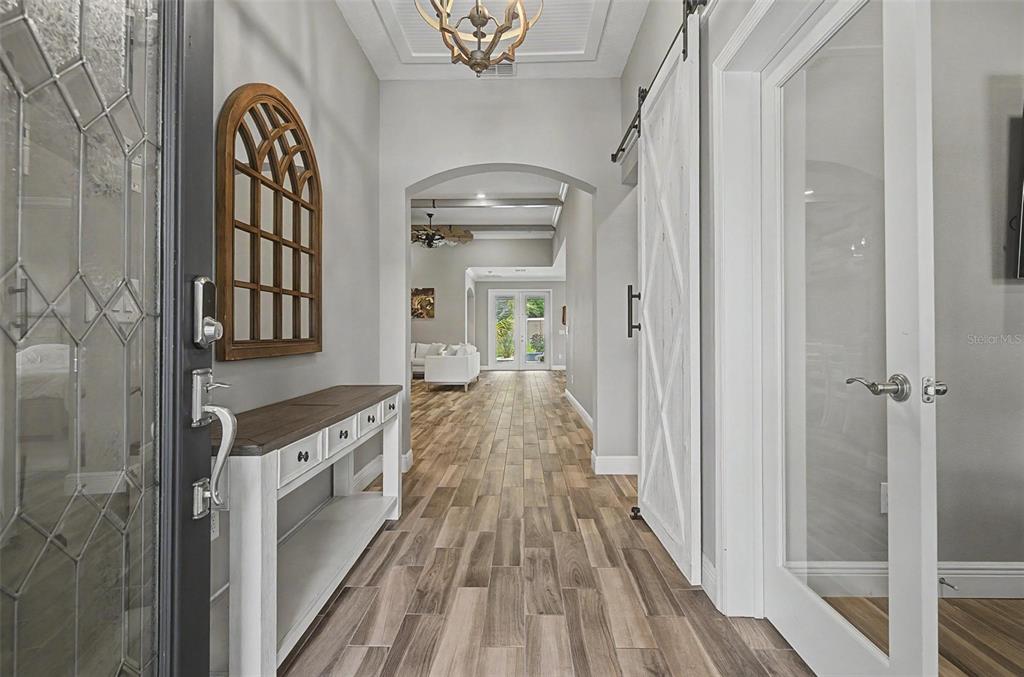 A foyer with wood-look tile flooring, a console table, and a white barn door — 11882 FROST ASTER DRIVE, RIVERVIEW, FL