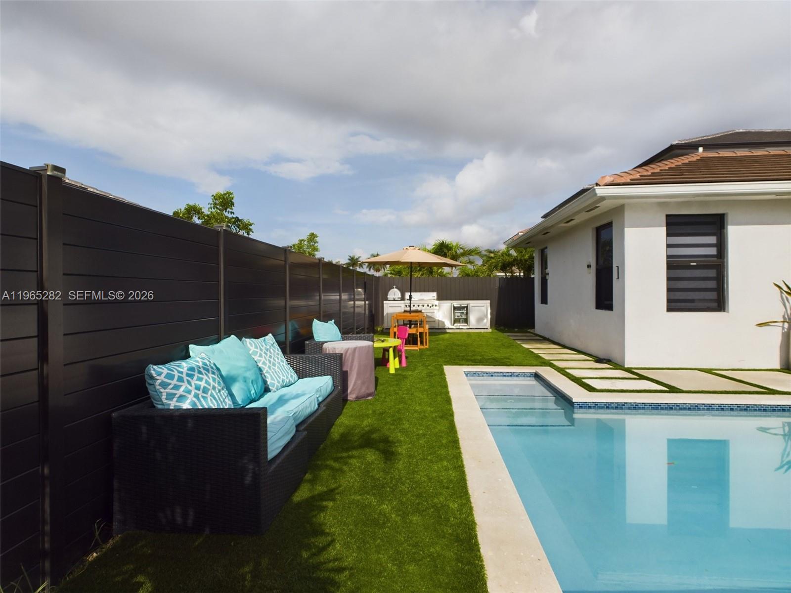 A backyard features a swimming pool, artificial turf, outdoor seating, and a grill station — 14560 SW 22nd Ter, Miami FL 33175, MIAMI, FL