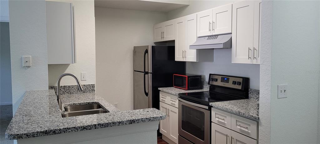 A kitchen features white cabinets, granite countertops, stainless steel appliances, and a breakfast bar — 17104 CARRINGTON PARK DRIVE UNIT 513, TAMPA, FL