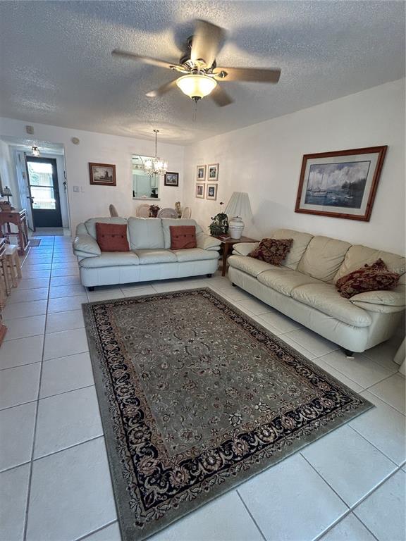 A living room features two light-colored sofas, a patterned area rug, and tile flooring — 11485 OAKHURST ROAD UNIT 200-318, LARGO, FL