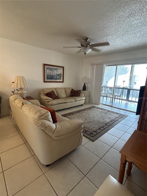 A living room features two beige leather sofas, a patterned area rug, and tile flooring — 11485 OAKHURST ROAD UNIT 200-318, LARGO, FL