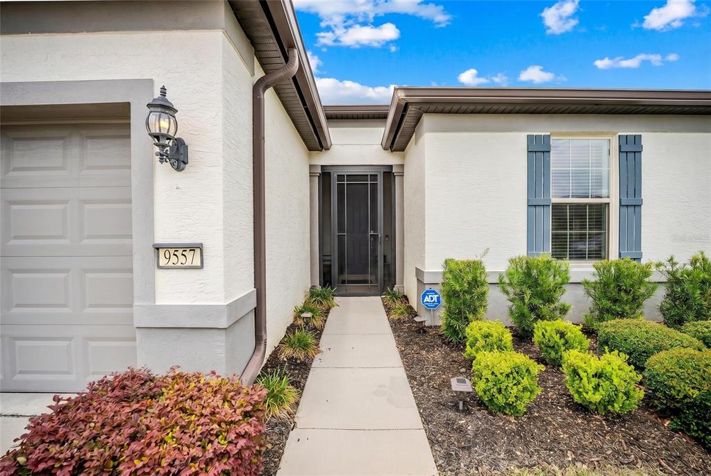 The exterior of a house features a concrete walkway leading to a front door — 9557 SW 64TH LANE, OCALA, FL