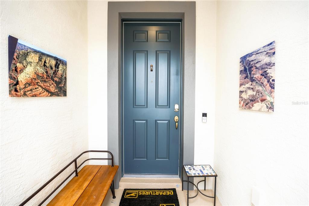 A blue front door with a wooden bench and two landscape wall art pieces — 9557 SW 64TH LANE, OCALA, FL