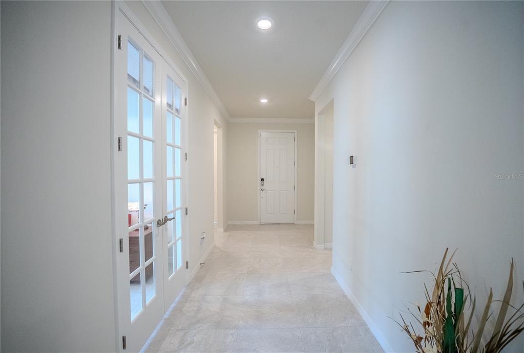 A bright hallway features light-colored tile flooring, white walls, and a set of French doors — 9557 SW 64TH LANE, OCALA, FL